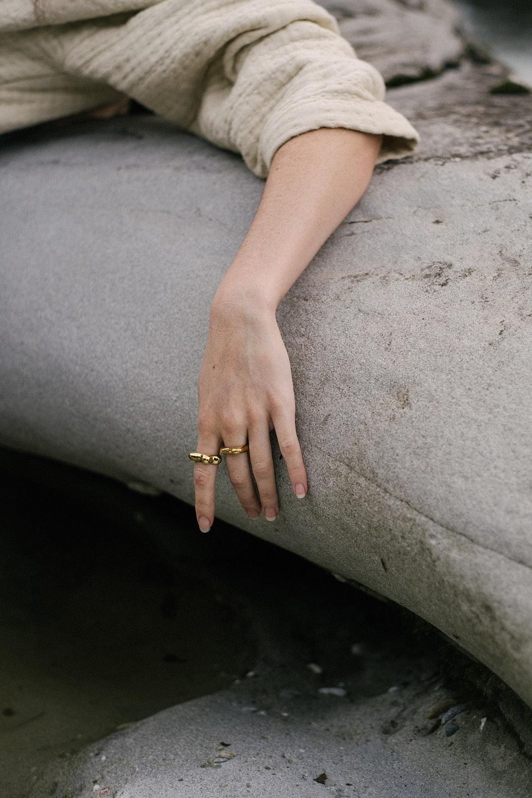 Hand wearing FLUID ring made of recycled gold and silver, showcasing ethical handmade jewelry in a natural setting.