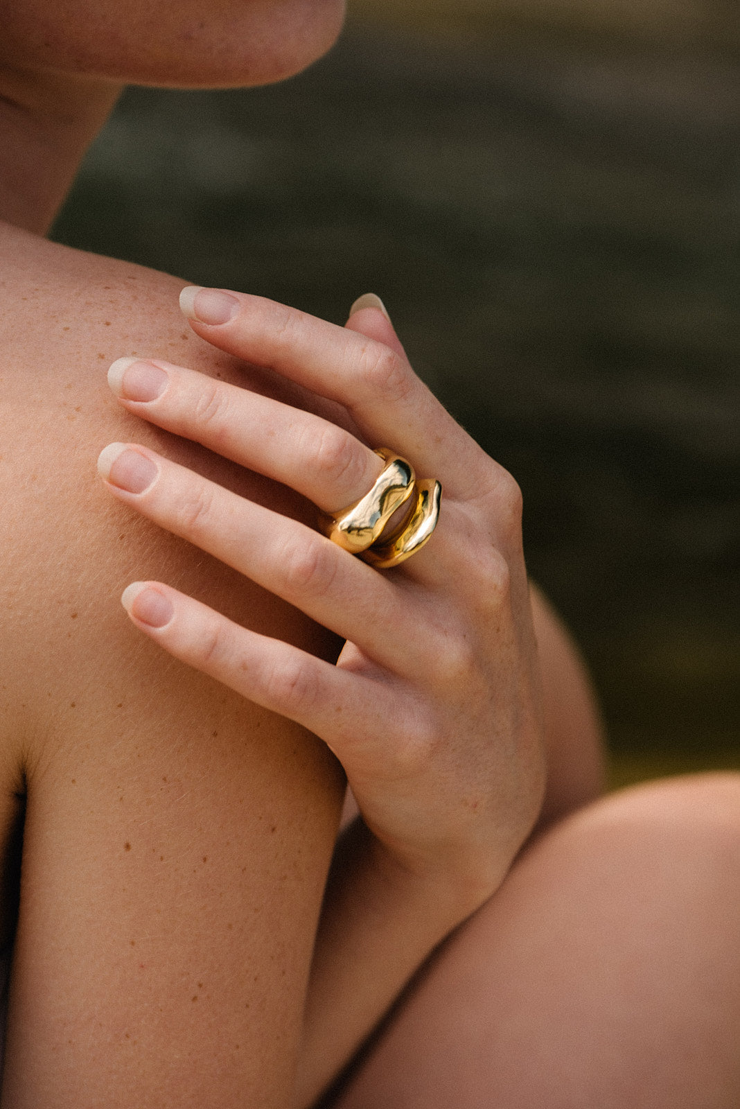 A close-up of a hand wearing a HALO ring made of 18k gold-plated recycled silver, highlighting its shiny finish.