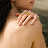 Model showcasing HALO ring on her finger against a natural backdrop, highlighting its sustainable design and gold finish.