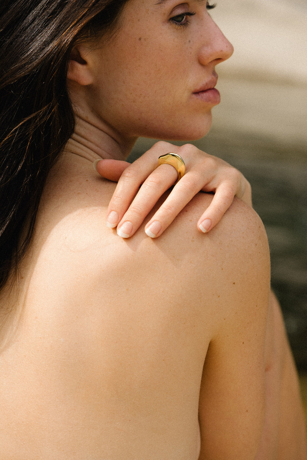 Model showcasing HALO ring on her finger against a natural backdrop, highlighting its sustainable design and gold finish.