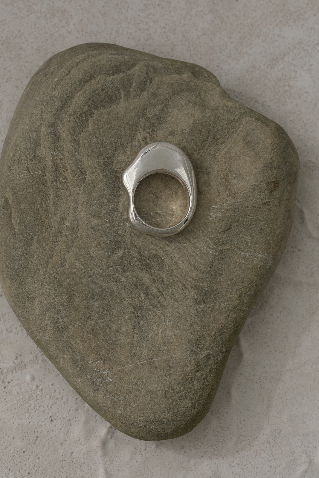 HALO ring in 925 recycled silver resting on a smooth stone, highlighting its sustainable and high-quality design.