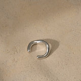 MISMO earcuff in recycled silver on textured surface, highlighting sustainable handmade ethical jewelry.