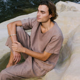 Stylish man wearing handmade ethical clothing by a river, showcasing sustainable fashion and natural beauty.