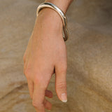 MUSA bangle in 925 recycled silver worn on a hand, showcasing ethical handmade jewelry with a natural shiny finish.