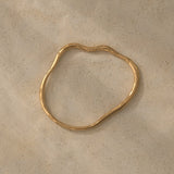 Handmade ethical jewelry PLACID bangle in 18k gold-plated recycled silver on a textured surface.
