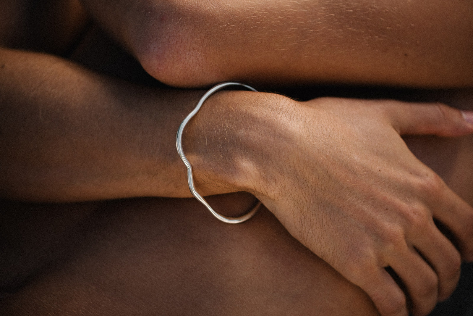 Handmade PLACID bangle in recycled silver, showcasing a natural shiny finish on a wrist.