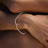Handmade PLACID bangle in recycled silver, showcasing a natural shiny finish on a wrist.