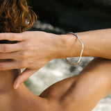 Handmade PLACID bangle in recycled silver, worn on a model's wrist, showcasing sustainable ethical jewelry.