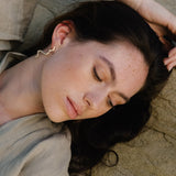 Model showcasing handmade PLACID earrings made of sustainable recycled gold and silver, featuring an elegant design.