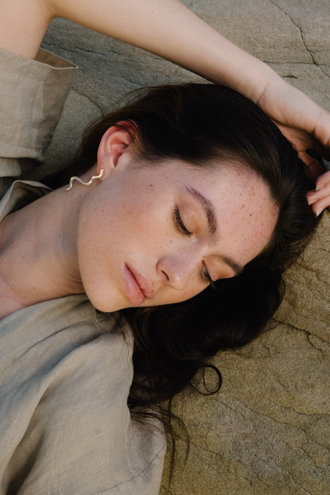 Model showcasing handmade PLACID earrings made of sustainable recycled gold and silver, featuring an elegant design.