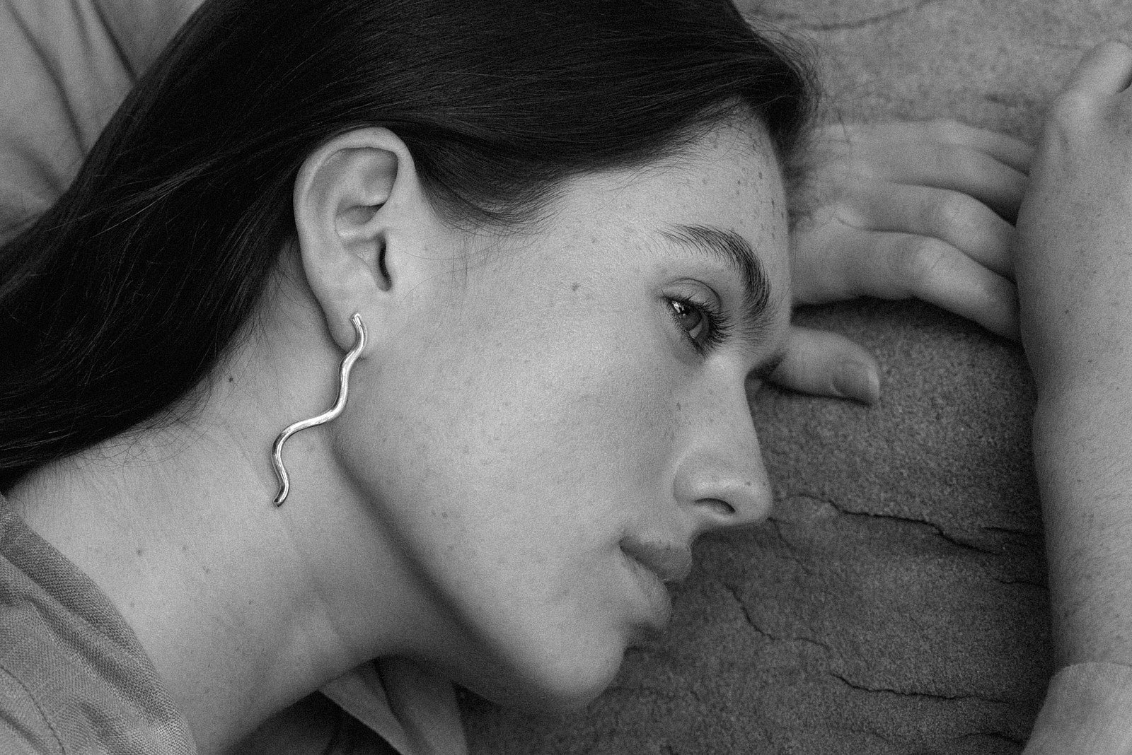 Model showcasing PLACID earrings, handmade from recycled gold and silver, emphasizing ethical jewelry craftsmanship.