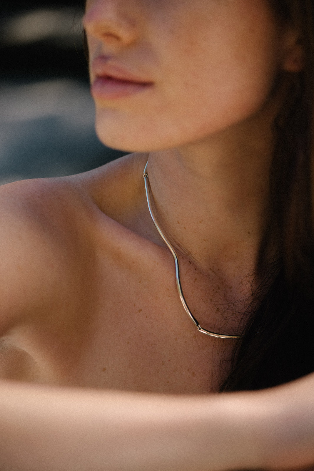 Close-up of a woman wearing the PLACID handmade necklace made of recycled silver, showcasing its elegant design and sustainable charm.
