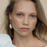 Model wearing EIRA duo earrings, handmade ethical jewelry in 18k gold-plated recycled silver for a sustainable look.