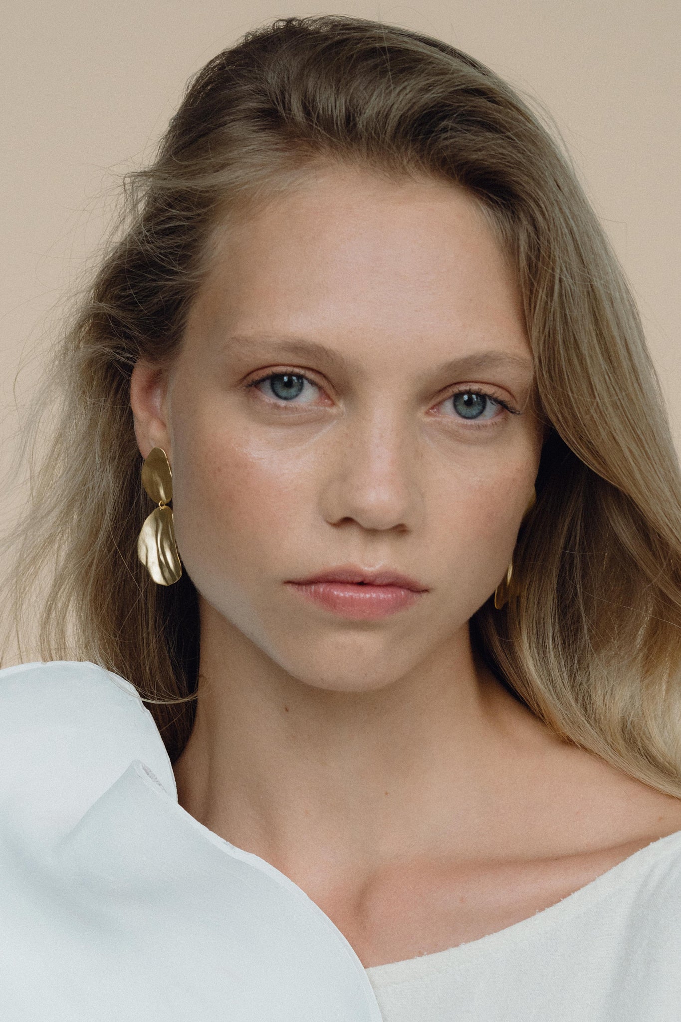 Model wearing EIRA duo earrings, handmade ethical jewelry in 18k gold-plated recycled silver for a sustainable look.