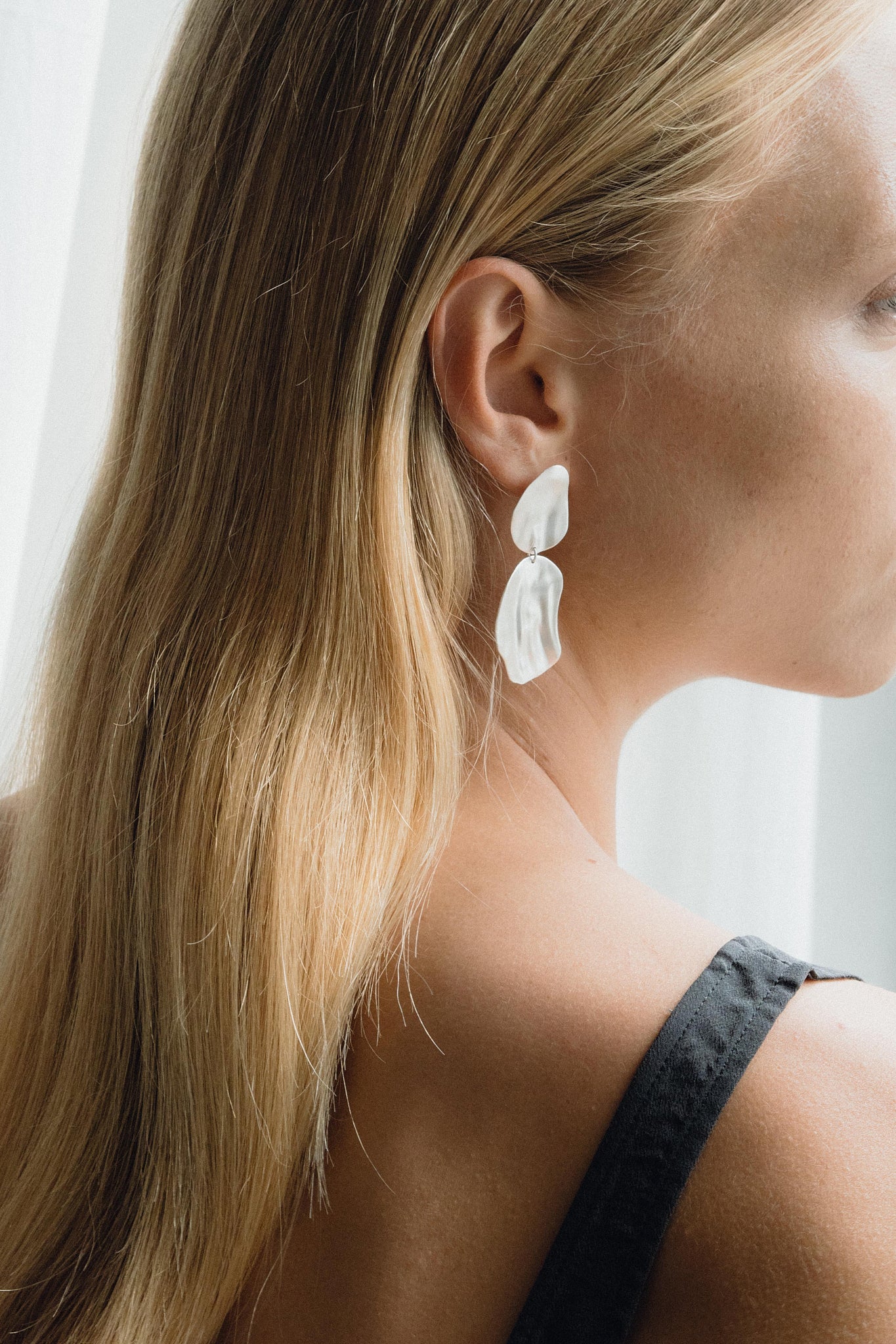 Elegant EIRA duo earrings in recycled gold and silver, showcasing sustainable handmade craftsmanship, worn by a model.