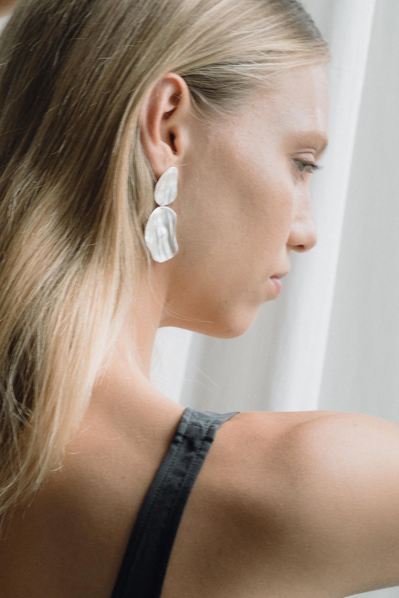Model showcasing EIRA duo earrings, handcrafted from recycled silver and gold, emphasizing sustainable and ethical jewelry.