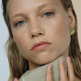 Model showcasing EIRA solo earrings, emphasizing sustainable, ethical jewelry made of recycled gold and silver.