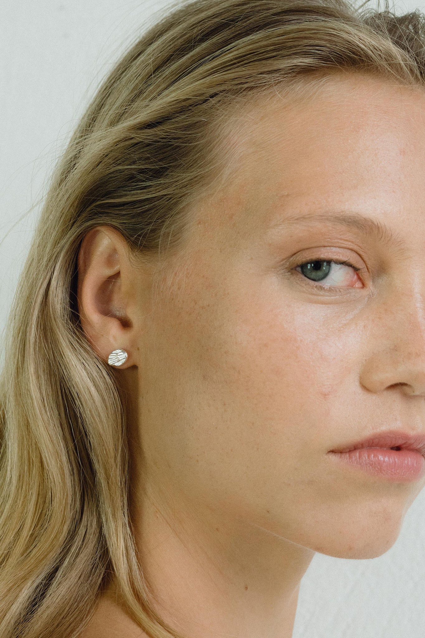 Close-up of a model wearing ELV earrings, showcasing ethical handmade jewelry in recycled gold and silver.