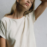 Model wearing neutral-toned ethical tee with LUMI big earrings, highlighting sustainable fashion and handmade jewelry.