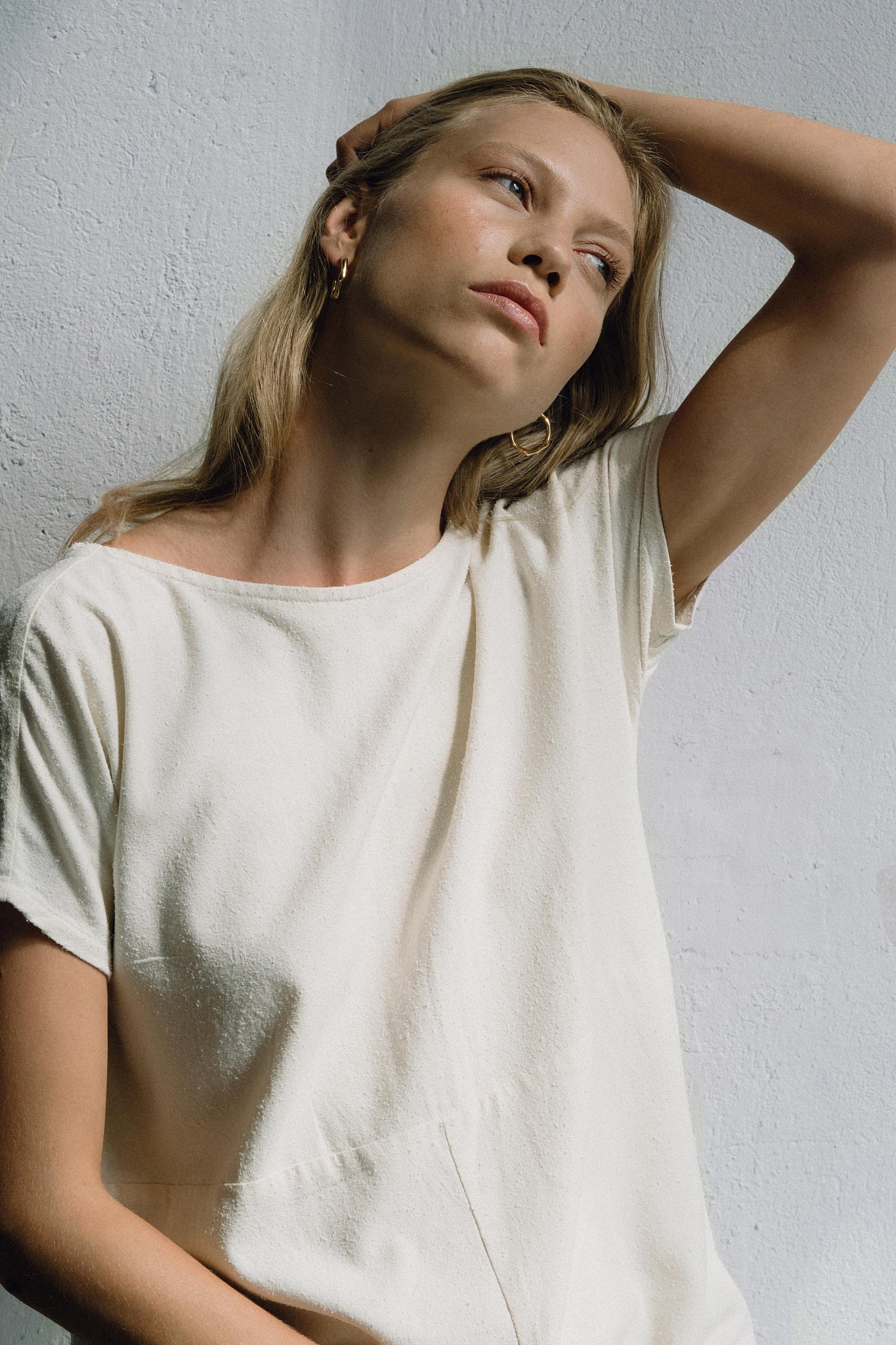 Model wearing neutral-toned ethical tee with LUMI big earrings, highlighting sustainable fashion and handmade jewelry.