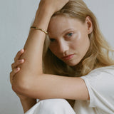 Model wearing LUMI cuff, an adjustable ethical jewelry piece made of recycled gold and silver.