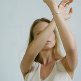 Model showcasing the LUMI cuff, an adjustable ethical jewelry piece made from recycled gold and silver.