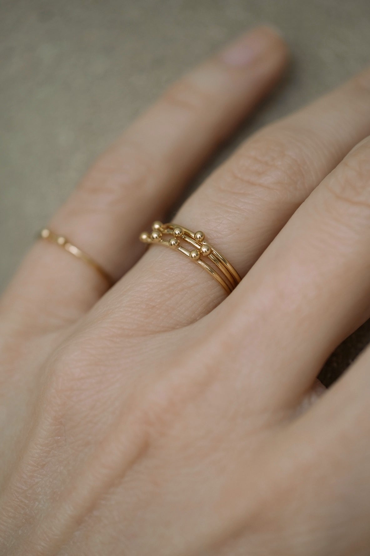 Handcrafted 18k recycled gold TINY PEBBLES ring worn on a hand, showcasing organic design from Basel, Switzerland.