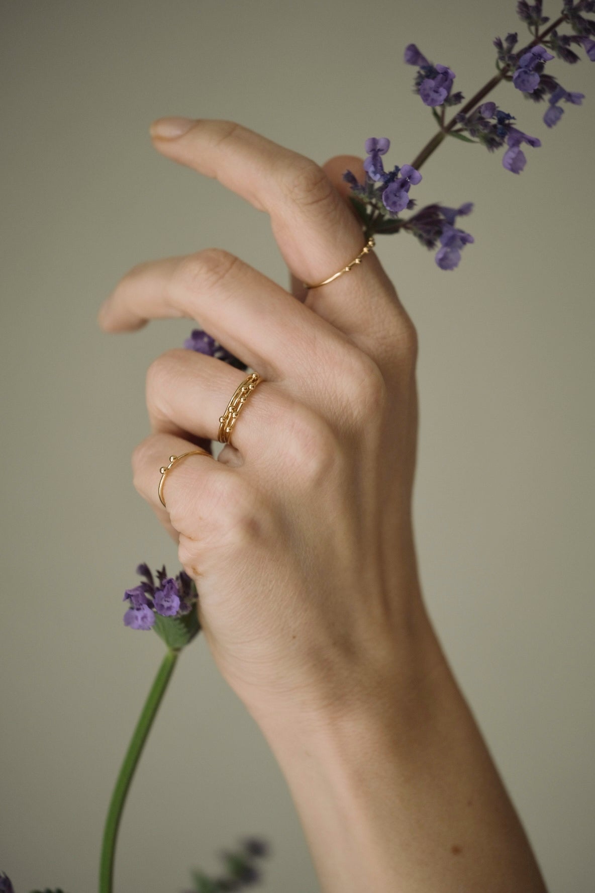 Hand wearing handcrafted 18k recycled gold rings, holding a flower, in Basel Switzerland.