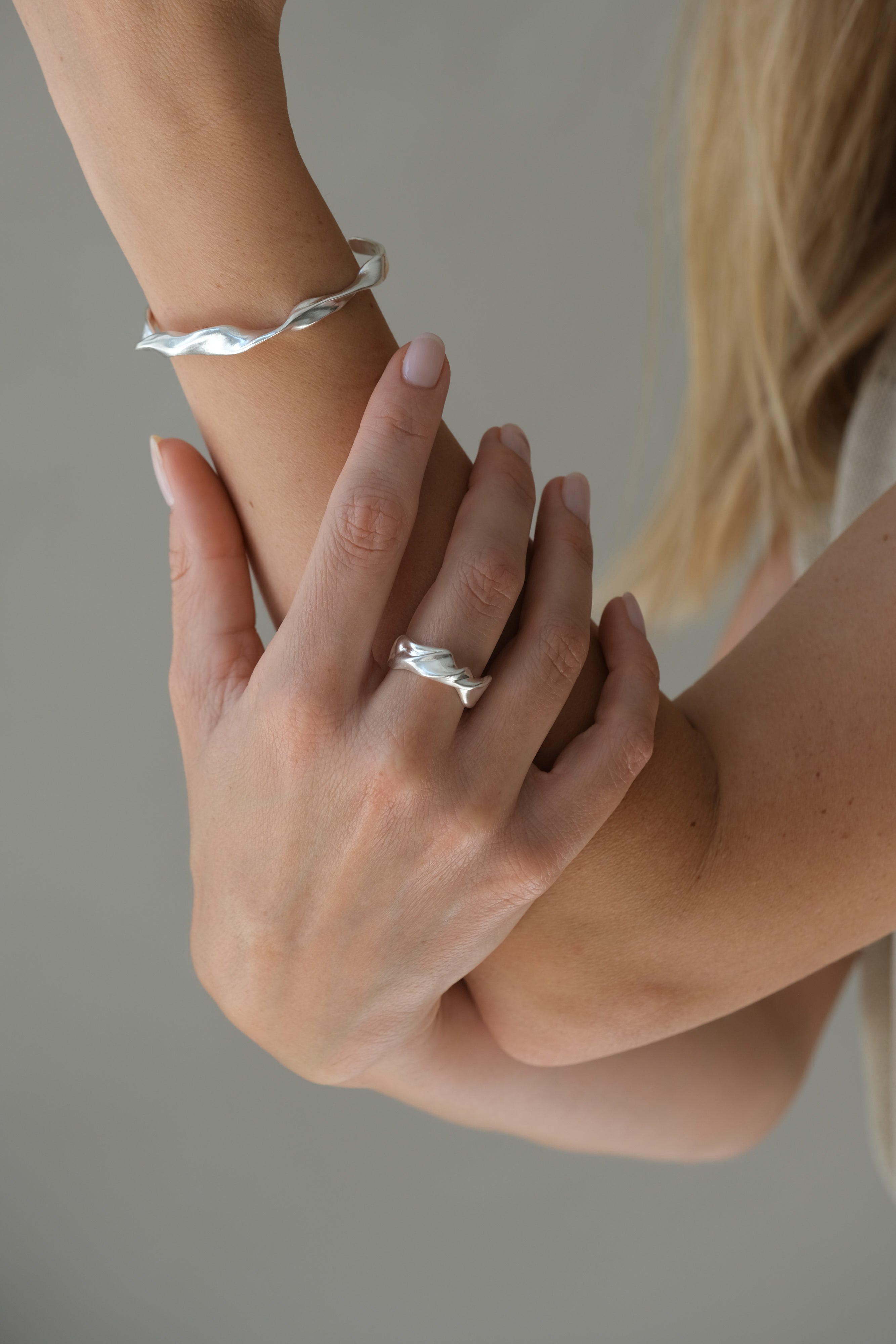 Hand model wearing DROP 04 bracelet and ring made of 925 recycled silver, showcasing unique handmade design in Basel.