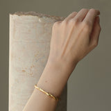 Hand wearing DROP 01 bracelet made of sustainable materials, 18k gold-plated on recycled silver, handmade in Basel.