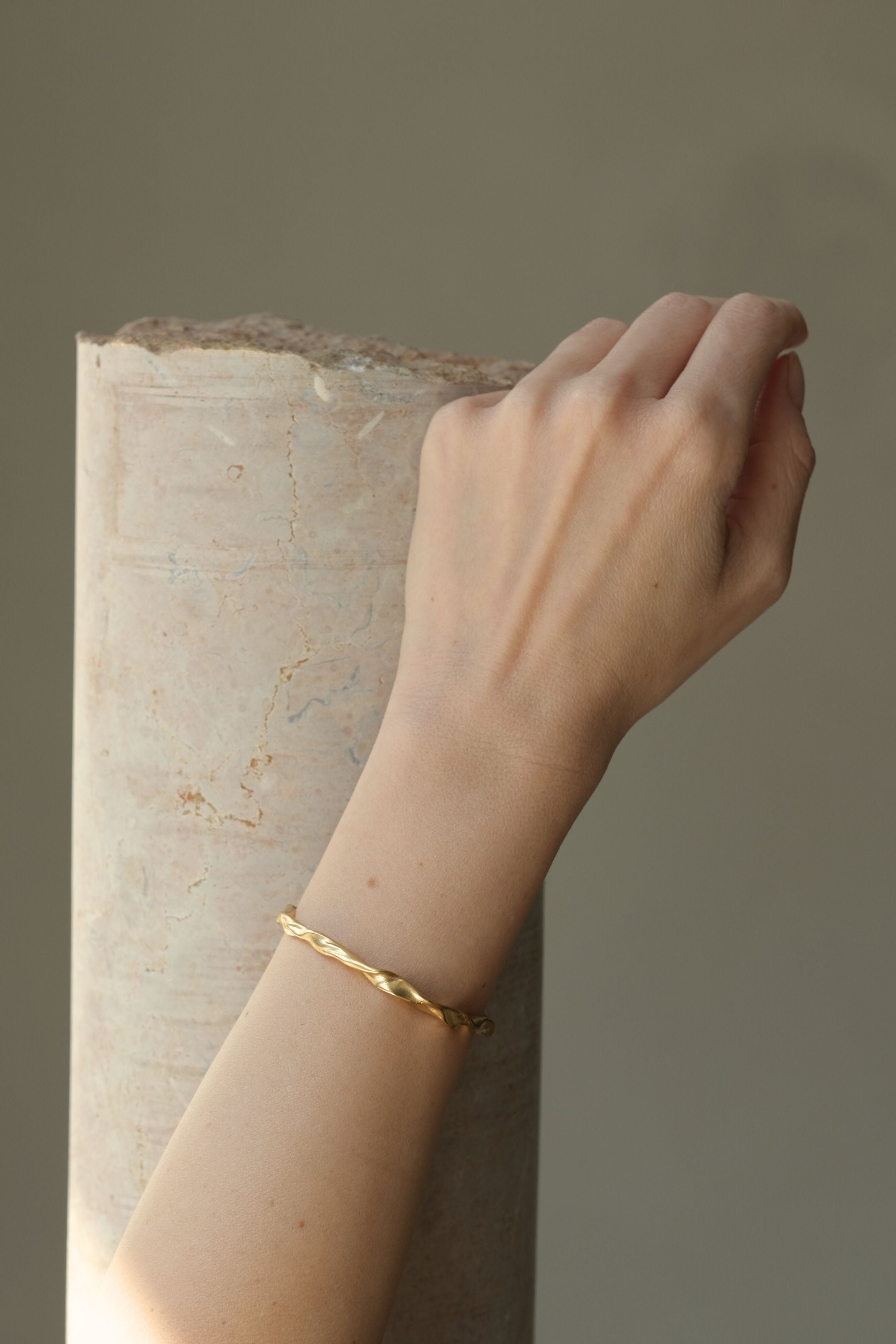 Hand wearing DROP 01 bracelet made of sustainable materials, 18k gold-plated on recycled silver, handmade in Basel.