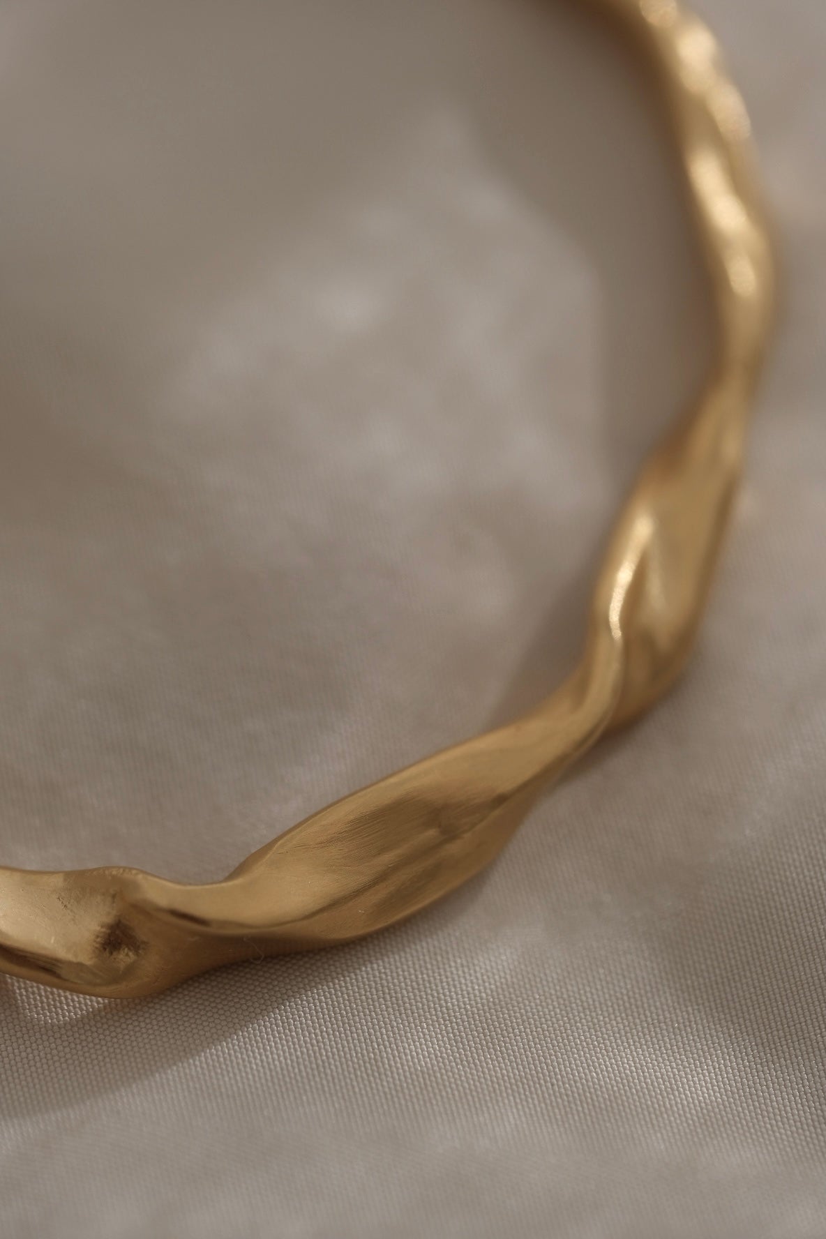 Close-up of a unique handmade gold-plated bracelet featuring an organic wave design, crafted in Basel, Switzerland.