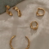 Handmade ethical and sustainable jewelry featuring gold-plated earrings and rings on soft fabric backdrop.