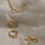 Unique handmade rings in 18k gold-plated recycled silver on soft fabric backdrop, showcasing ethical sustainable jewelry.