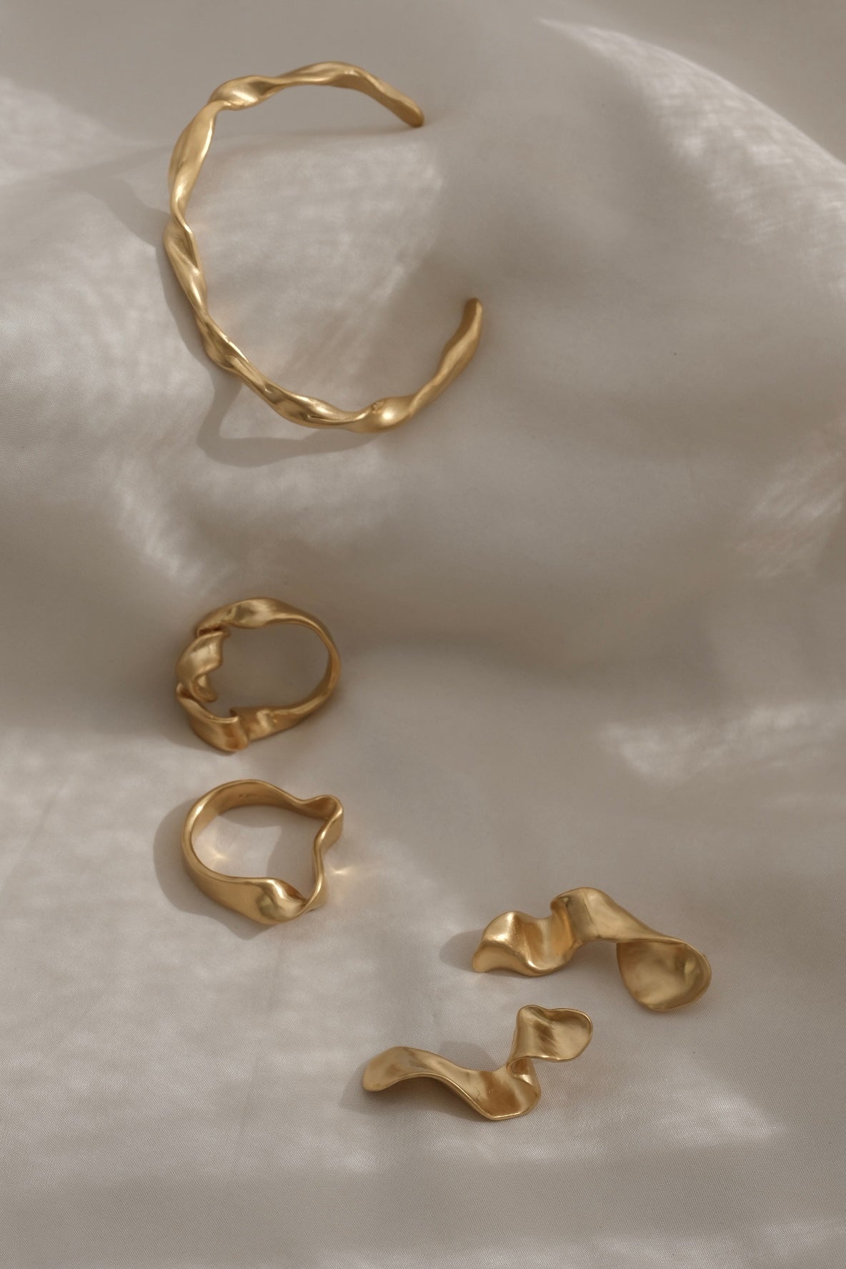 Unique handmade rings in 18k gold-plated recycled silver on soft fabric backdrop, showcasing ethical sustainable jewelry.
