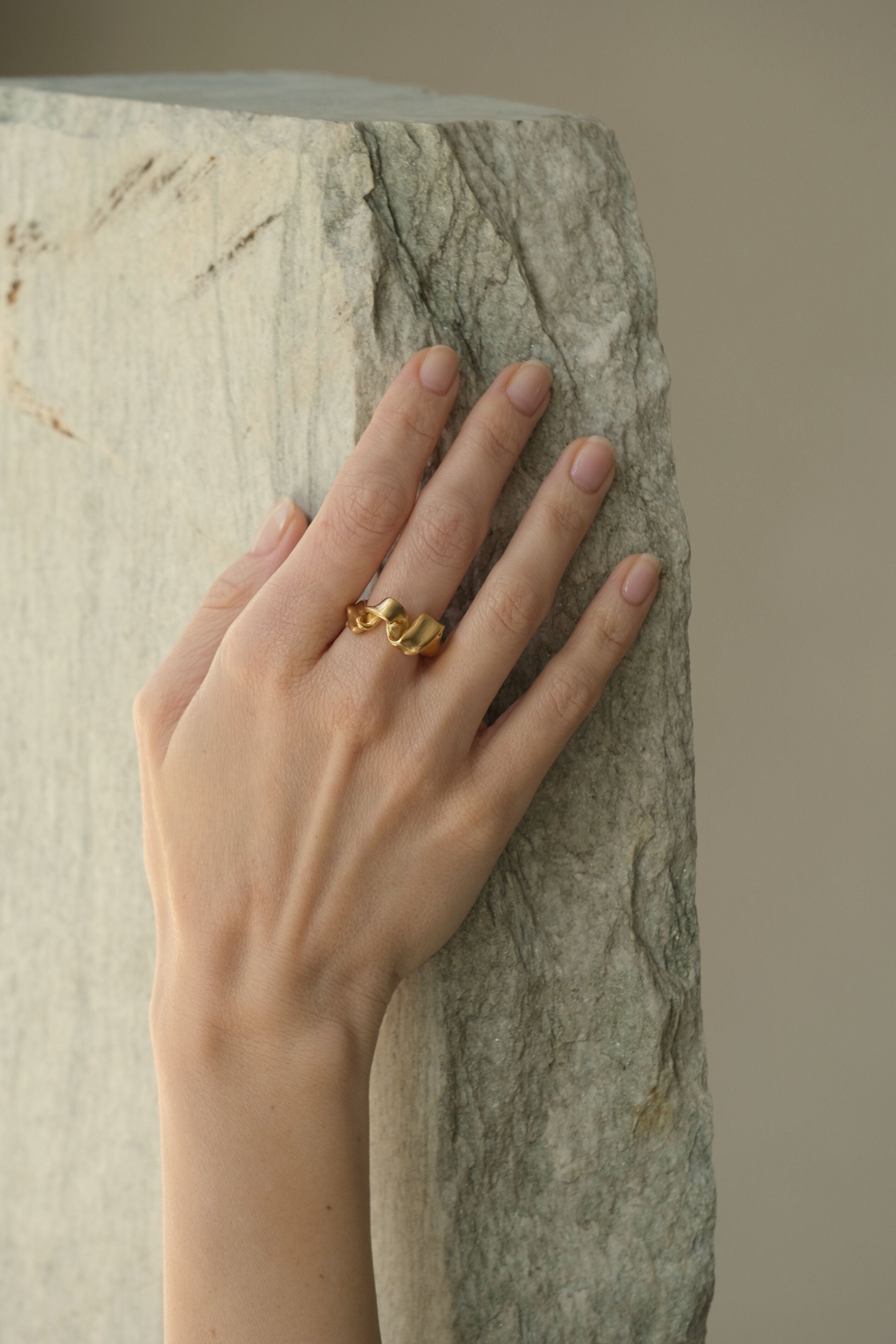 Hand wearing DROP 01 ring made of 18k gold-plated recycled silver, showcasing unique ethical jewelry.