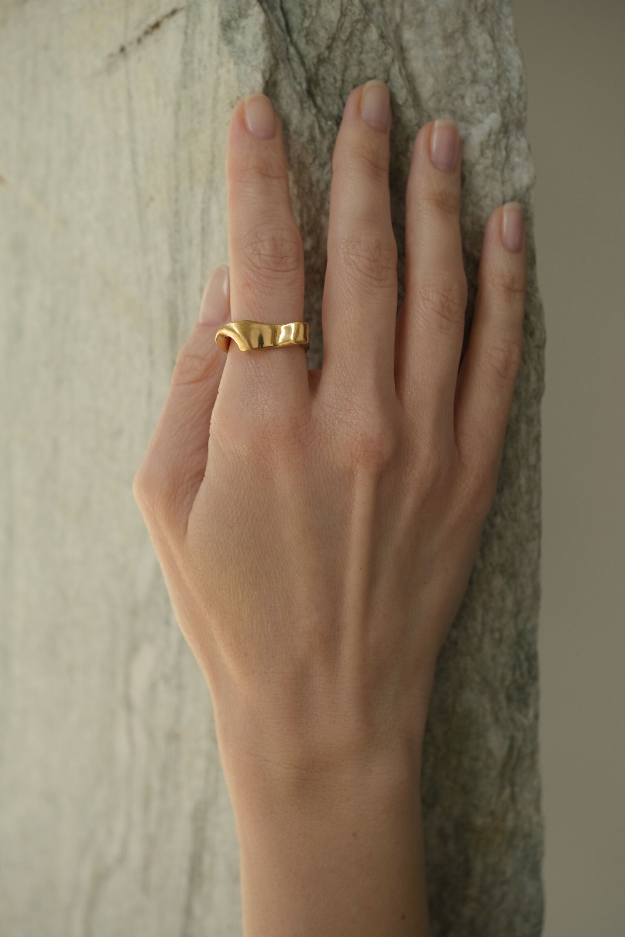 Hand wearing the DROP 01 ring, a unique handmade piece in 18k gold-plated recycled silver, designed in Basel, Switzerland.