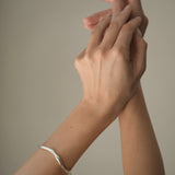 Elegant DROP 02 bracelet showcased on hands, crafted from sustainable 925 recycled silver in Basel, Switzerland.