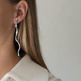 Unique handmade earrings in 925 recycled silver, showcasing an organic shape, styled by a model with long hair.