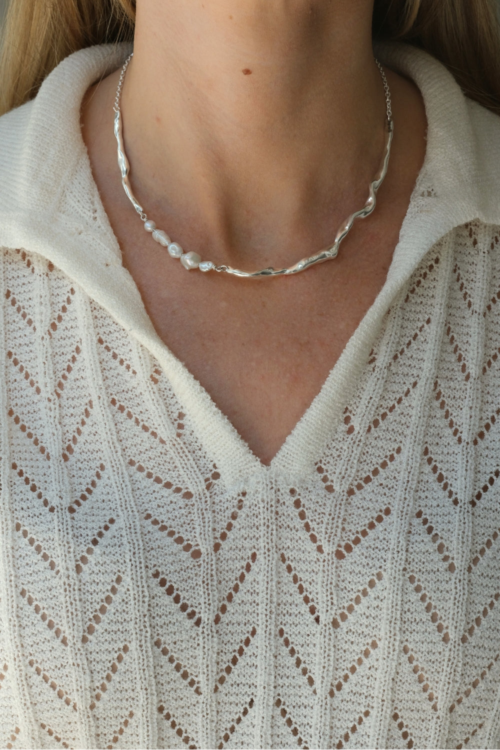 Handmade DROP 02 necklace in recycled silver, showcasing unique imperfections, worn on a woman in a cozy knit top.