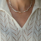 Handmade DROP 02 necklace in recycled silver, showcasing unique imperfections, worn on a woman in a cozy knit top.