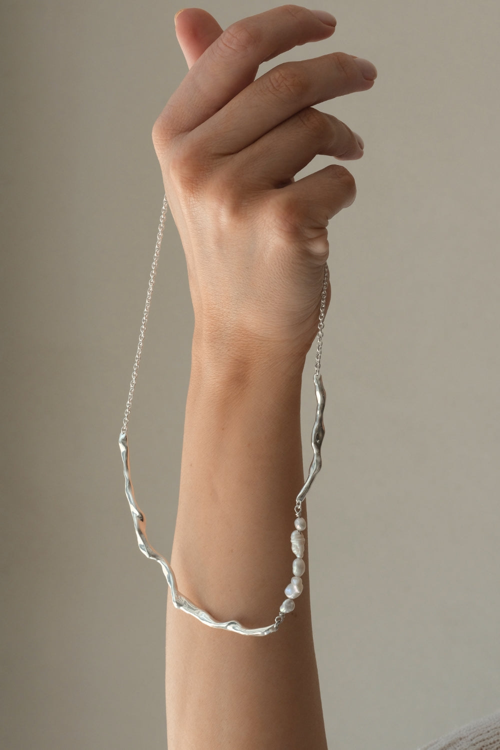 Hand holding DROP 02 necklace, handmade in Basel, featuring 925 recycled silver and unique design.
