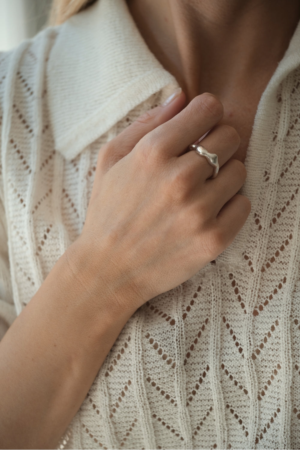 Hand wearing DROP 02 ring, showcasing unique handmade design in 925 recycled silver, styled with a knit top.