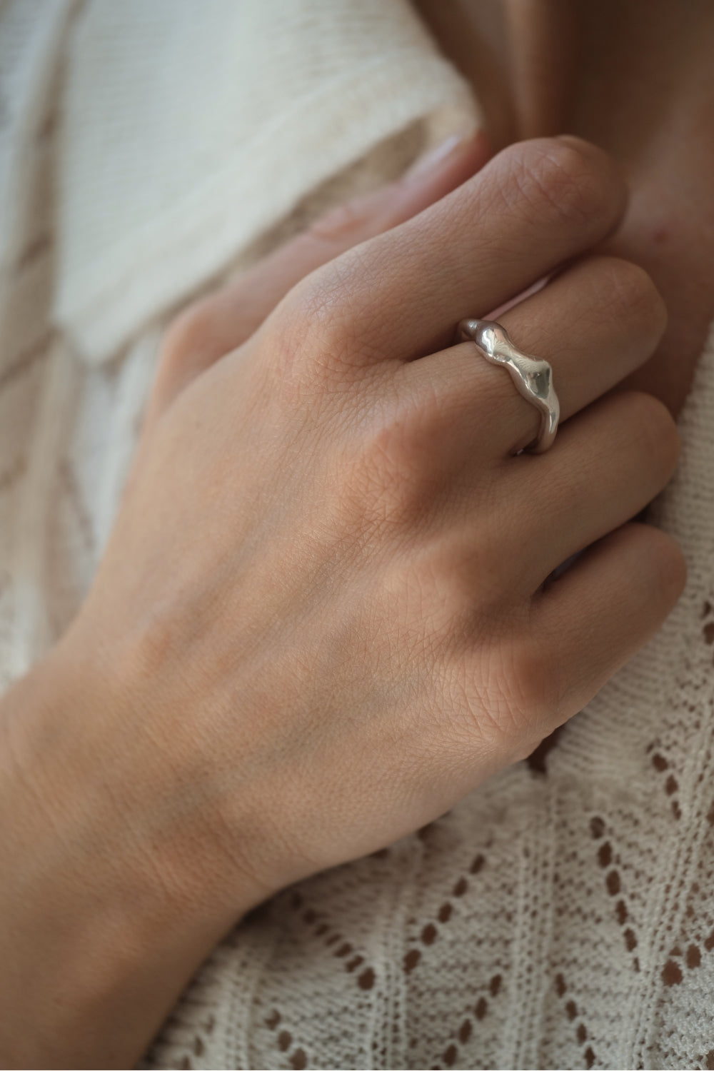 Hand wearing DROP 02 ring made of 925 recycled silver, showcasing unique design and natural shiny finish.