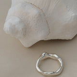 Handmade ring in 925 recycled silver next to a seashell, showcasing unique, ethical jewelry from Basel, Switzerland.