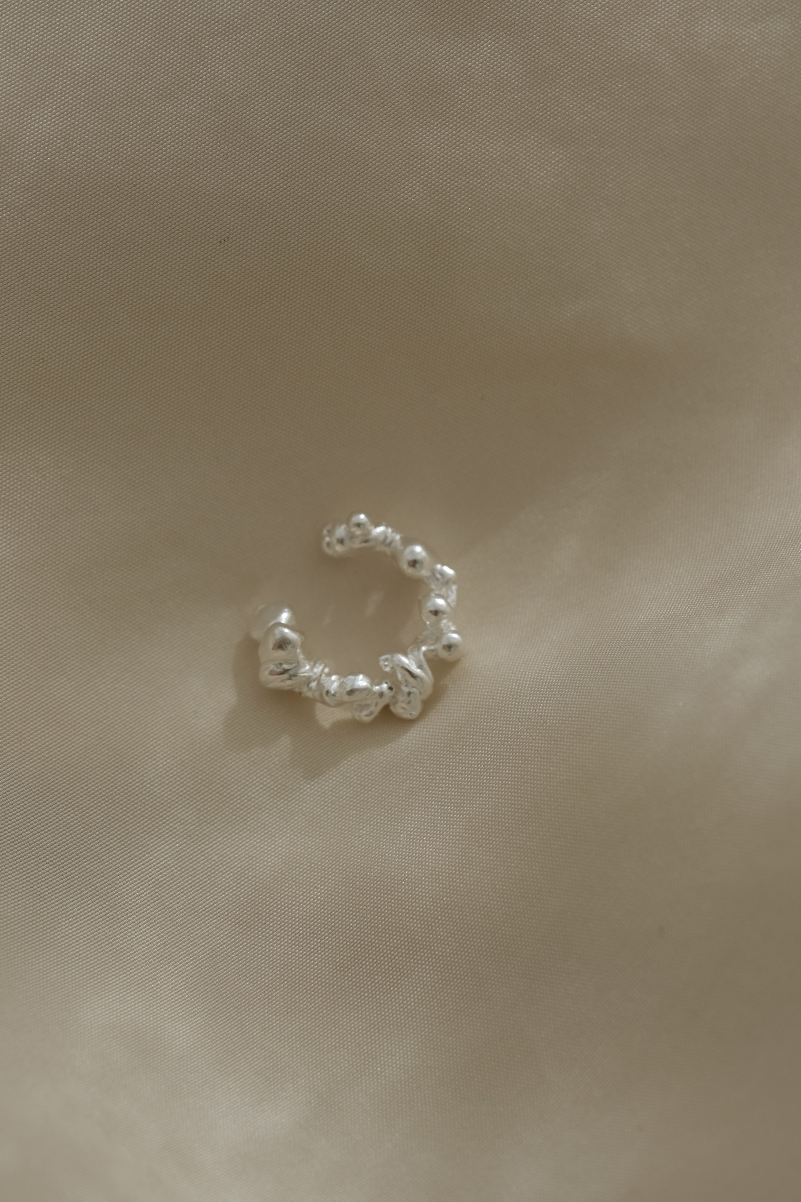 Handmade ear cuff in 925 recycled silver, featuring unique design and satin finish, made in Basel, Switzerland.