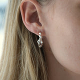 Ethical and sustainable jewelry, handmade 925 recycled silver earrings worn on women's ear in Basel, Switzerland.