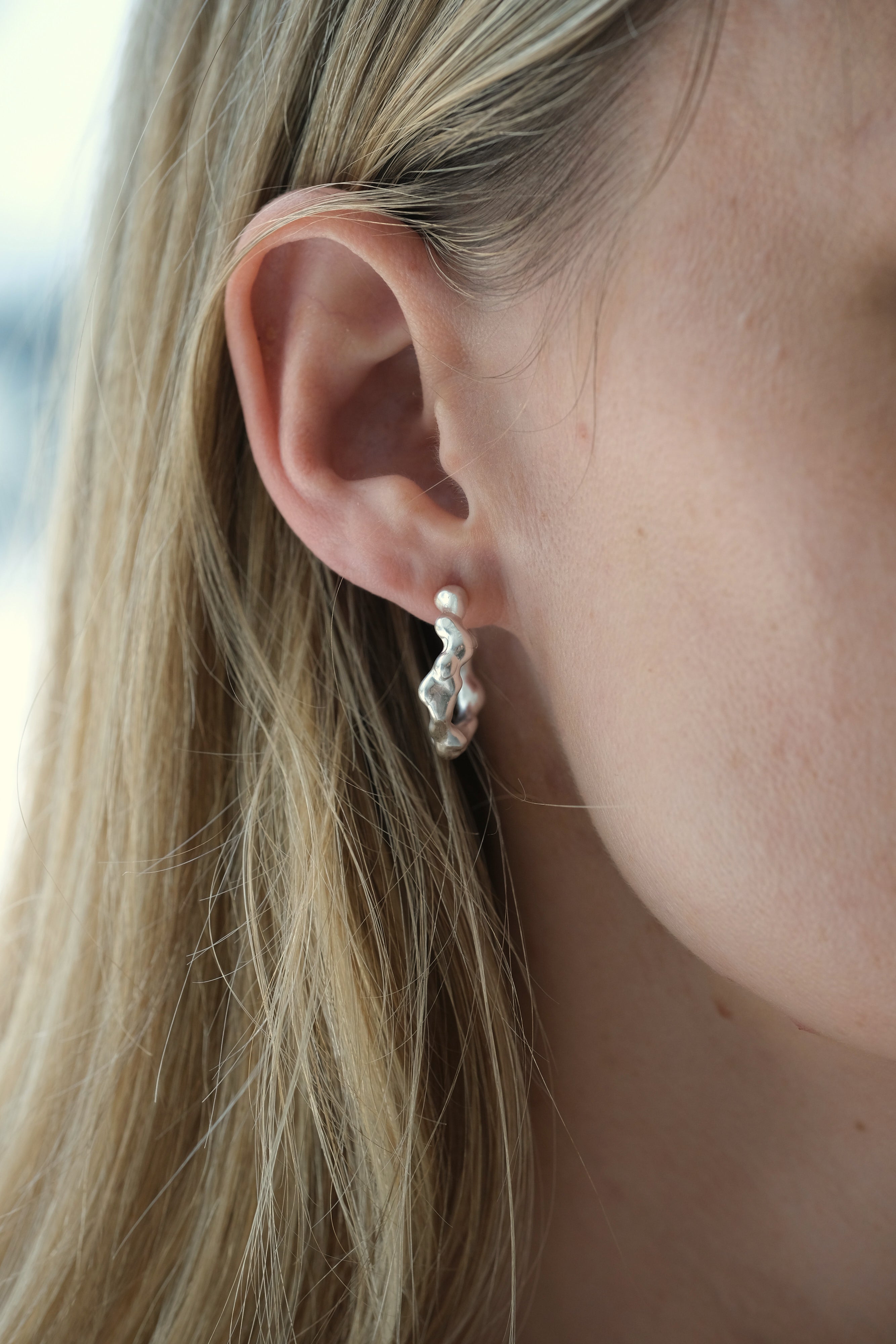 Ethical and sustainable jewelry, handmade 925 recycled silver earrings worn on women's ear in Basel, Switzerland.