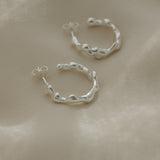Handmade ethical earrings in recycled silver, featuring a unique organic shape and polished finish, made in Basel, Switzerland.