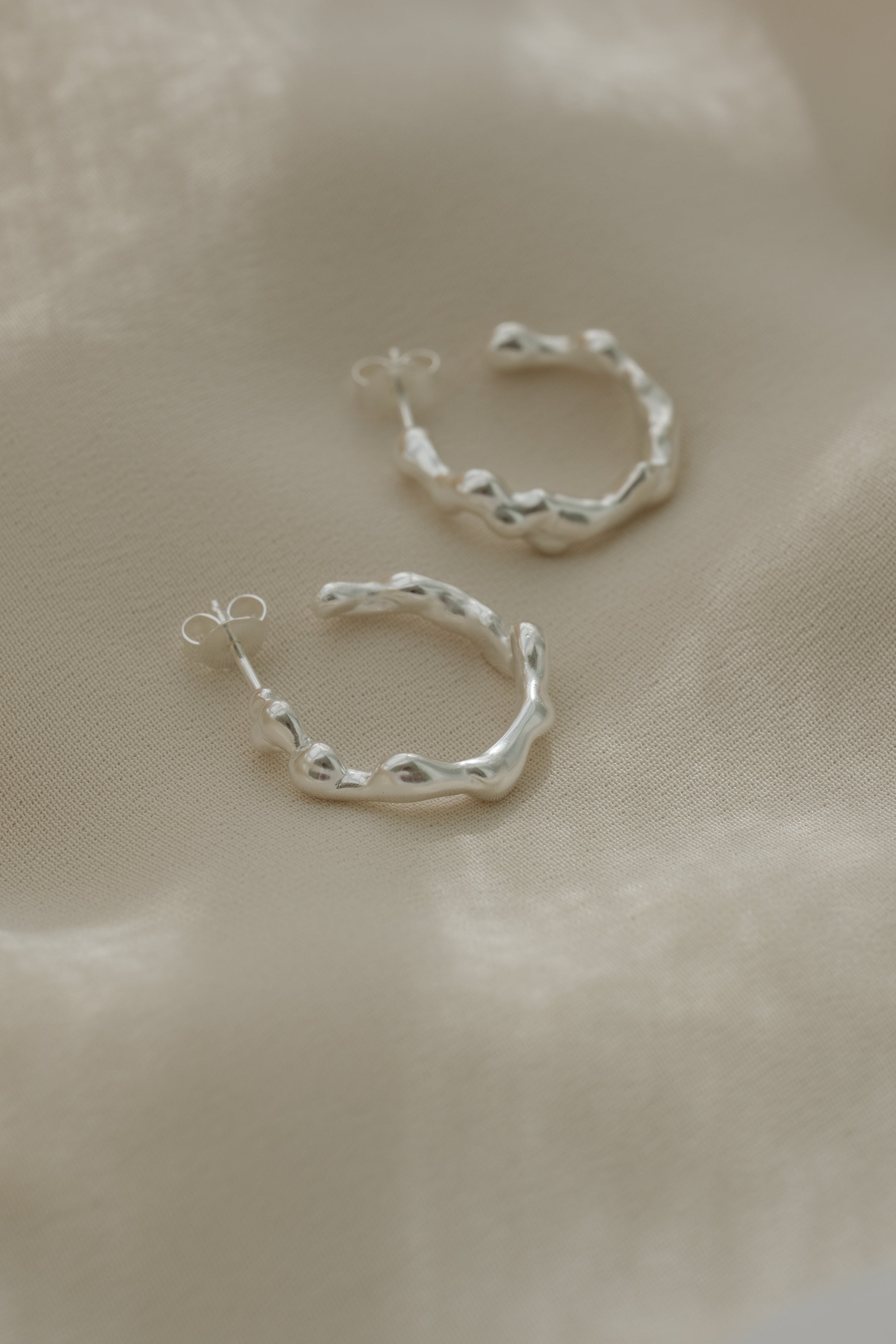 Handmade ethical earrings in recycled silver, featuring a unique organic shape and polished finish, made in Basel, Switzerland.